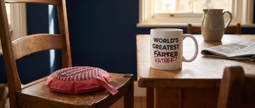 A whoopee cushion waiting on a dining chair beside a novelty joke mug on a family table
