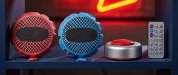 A row of whoopee cushions, a remote fart machine and its remote on a navy shelf