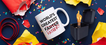 A novelty joke mug and a black prank gift box on a navy table with confetti